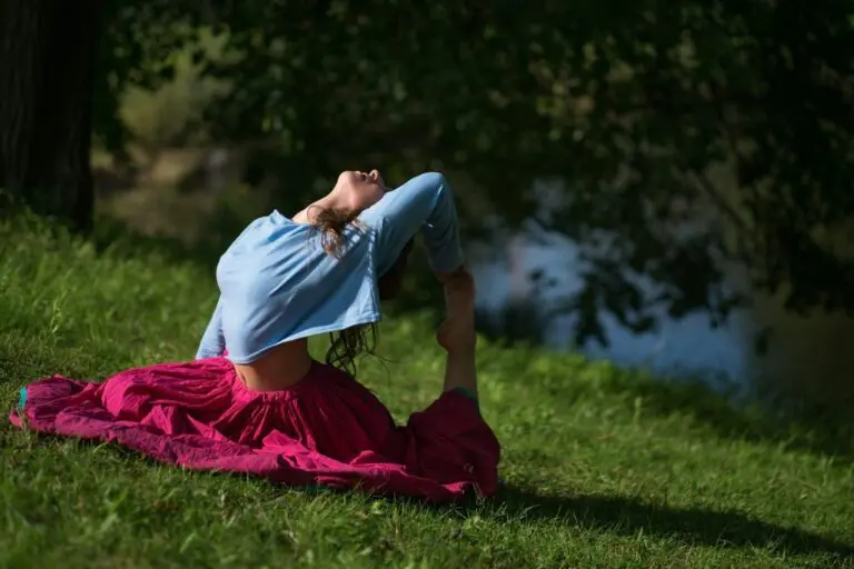 Beautiful young woman in red skirt practicing Yoga asana in nature