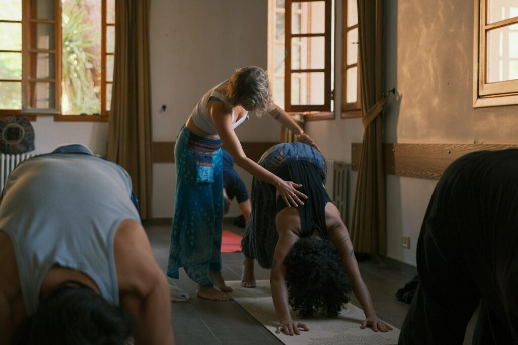 Yoga instructor assisting student in downward dog pose.