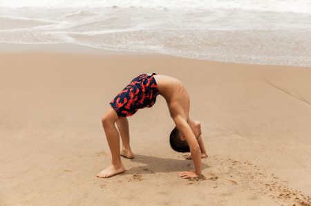 Healthy young boy practicing yoga on the beach, California