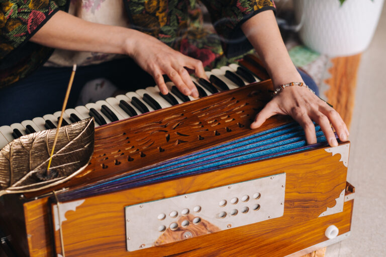Hands of a woman sitting on the floor and playing the harmonium during the practice of kundalini